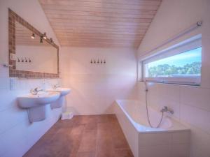 a bathroom with two sinks and a tub and a window at XXL Familienferienhaus in Granzow +24 photos