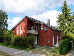 a red barn with a balcony and a tree at XXL Familienferienhaus in Granzow