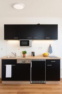 una cucina con armadi neri e lavandino di Dat-Fischerhuus-das-Fischerstuebchen-zwischen-Ostsee-und-Bodden-20sek-zum-Hafen a Pruchten