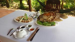 a white table with two plates of food on it at Ba Linh Homestay in Vĩnh Long