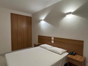 a bedroom with a bed and two lights on the wall at Transamerica Araraquara in Araraquara