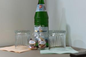 エッカーンフェルデにあるHotel Seepferdchen Zimmer 1 Eckernförde Self-Check-Inの緑のボトルとテーブルの上にグラス2杯
