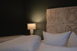 una cama con almohadas blancas y una lámpara junto a ella en Hotel Seepferdchen Zimmer 6 Eckernförde Self-Check-In, en Eckernförde