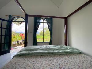 Djojo Bungalow في Timbanglawang: غرفة نوم مع سرير مظلة مع نافذة كبيرة