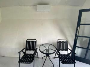 Djojo Bungalow في Timbanglawang: كرسيين وطاولة زجاجية في الغرفة