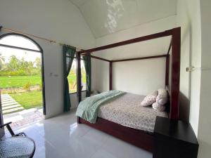 Djojo Bungalow في Timbanglawang: غرفة نوم بها سرير ونافذة كبيرة