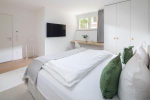 a white bedroom with a large white bed with pillows at Strandhaus Südwesthörn in Norderney