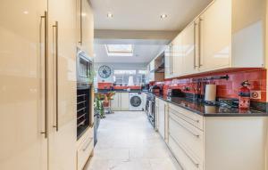 uma grande cozinha com armários brancos e paredes vermelhas em Hot Tub and Garden Spacious Unique 3 Bed House em Allesley