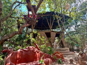 a red statue in front of a house with a tree at Mapu in Pipa +99 photos