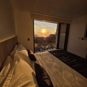 a bedroom with a bed and a window with a sunset at Arka Hotel in Viña del Mar
