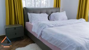 2 bedden met witte lakens en kussens in een slaapkamer bij Lizabon Apartment Arusha in Nkoanrua +18 foto's