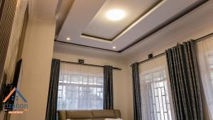 een woonkamer met een gepaneeld plafond en ramen bij Lizabon Apartment Arusha in Nkoanrua