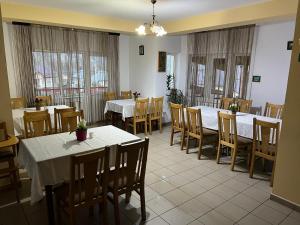a dining room with tables and chairs and windows at Pension Nicoleta in Costeşti