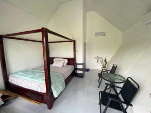 Djojo Bungalow في Timbanglawang: غرفة نوم بها سرير وطاولة وكرسي