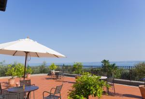 Un patio con mesas y sillas y una sombrilla. en San Rocco Relais, en Soiano del Lago