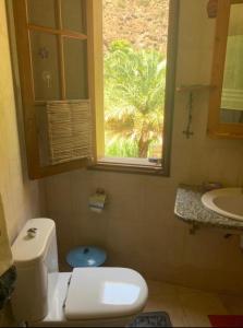 Un baño con inodoro, lavabo y ventana. en Wahnon Guesthouse, en Paul