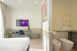 a bathroom with a bed and a toilet and a tv at Proja Housing Romagnosi20 in Rome +84 photos