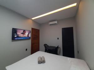 a bedroom with a bed with a tv on the wall at Morada 1 do Jardim do Éden in Parnaíba
