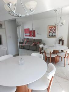 ein Wohnzimmer mit weißen Tischen und Stühlen sowie einem Sofa in der Unterkunft Apartamento SUN - Barra Norte in Balneário Camboriú