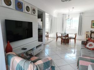 ein Wohnzimmer mit einem großen TV und einem Tisch in der Unterkunft Apartamento SUN - Barra Norte in Balneário Camboriú