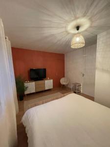 una camera da letto con un letto bianco e una televisione di Cocon de douceur a La Ravoire