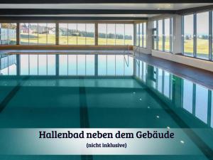 a swimming pool in a building with glass windows at Gemütliches Apartment mit wundervollem Weitblick in Löffingen