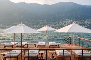 a group of tables and chairs with umbrellas on the water at Mandarin Oriental, Lago di Como in Blevio