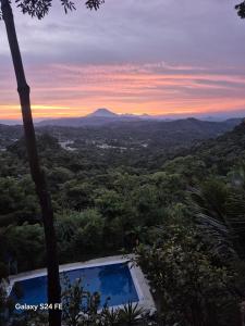 Una vista de una puesta de sol desde un resort con piscina. en Cabañas La Puerta Del Angel, 