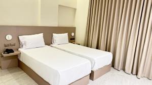 Dos camas en una habitación de hotel con cortinas. en Viaje Hotel Downtown Cairo, en El Cairo