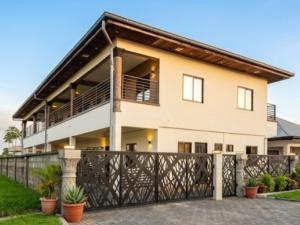 a large white house with a black fence at Sissa Omi Apartments in Wanica