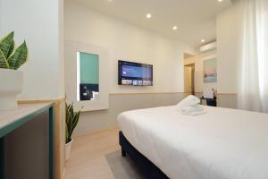 a bedroom with a large white bed and a tv at Proja Housing Romagnosi20 in Rome