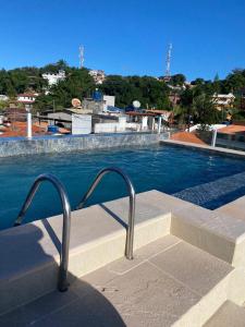 a swimming pool with a metal hand rail next to it at Apartamento Gute Morro - Praça Central in Cairu