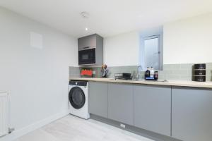 a white kitchen with a washing machine and a microwave at Large 4-Bedroom House in Banbury in Banbury