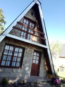 a house with windows and a dog sitting in the doorway at Cabañas Terra Natura in Bialet Massé