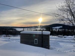 a small shed in the snow with the sun in the sky at Tiny house on wheels with great views Sjusjøen Minihus med utsikt Sjusjøen in Mesnali