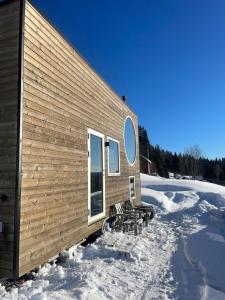 a cabin in the snow with benches next to it at Tiny house on wheels with great views Sjusjøen Minihus med utsikt Sjusjøen in Mesnali