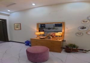 un soggiorno con uno sgabello viola e uno specchio di Giga Apartments & Sapphire Suite a Rawalpindi