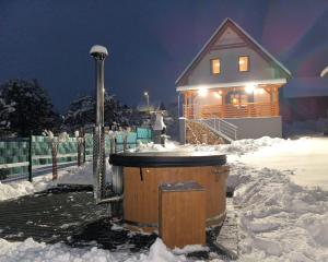 a hot tub in the snow in front of a house at Chata Závažka in Závažná Poruba