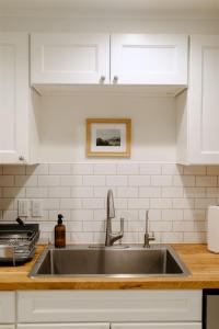 eine Spüle aus Edelstahl in einer Küche mit weißen Schränken in der Unterkunft Boxwood Haven in Moscow + 35 Fotos