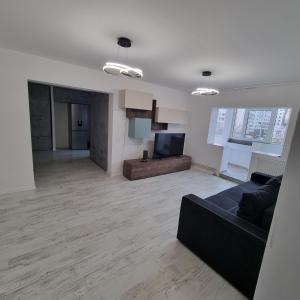 a living room with a black couch and a television at Ploiesti Central Apartament in Ploieşti