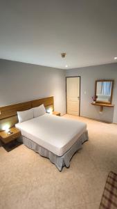 Un dormitorio con una gran cama blanca y un espejo. en Hotel Playa Parguito, en La Sabana