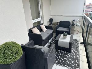 米卢斯F2 Cosy avec Terrasse à deux pas du centre de Mulhouse的阳台设有带藤椅和桌子的庭院