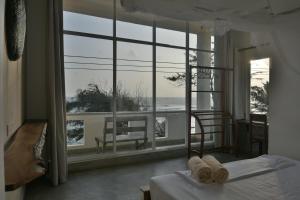 a bedroom with a view of the ocean from a window at The Stables Oceanfront Hotel Midigama in Midigama East