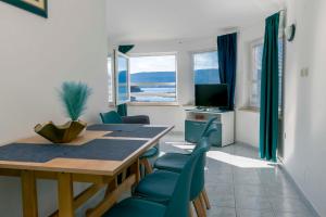 a dining room with a table and chairs and a television at Apartments Beach house Blace in Blace