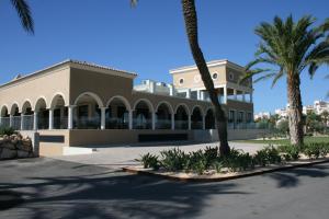 a building with palm trees in front of it at Hotel AR Golf Almerimar in Almerimar