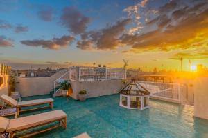 einen Balkon mit Blick auf die Stadt bei Sonnenuntergang in der Unterkunft Riad du Rabbin in Marrakesch