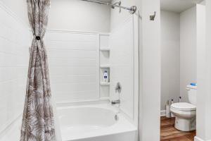 a white bathroom with a shower and a toilet at Explore Baton Rouge and LSU Family Home with Yard in Baker +17 photos