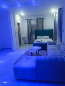 ein blaues Wohnzimmer mit einem Sofa und einem Bett in der Unterkunft TJ street studio apartment in Mtwapa