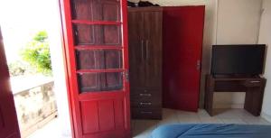 Una puerta roja que conduce a un dormitorio con un televisor. en Zona Estadio Azulgrana para concierto de Shakira, en Asunción