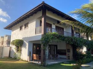 un edificio bianco con balcone e palma di Casa encanto dos corais a Trairi